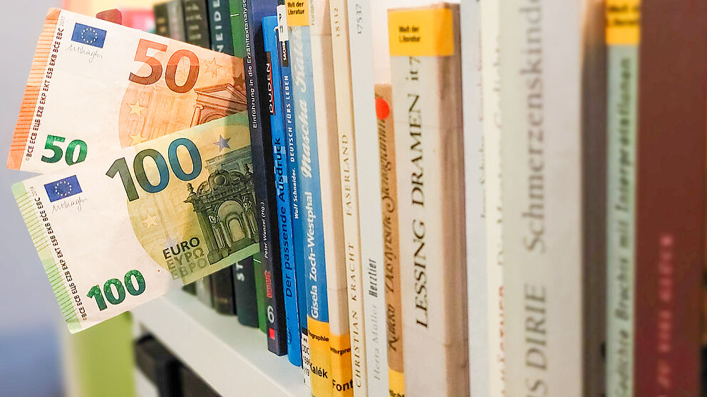 Geld zwischen Büchern. 